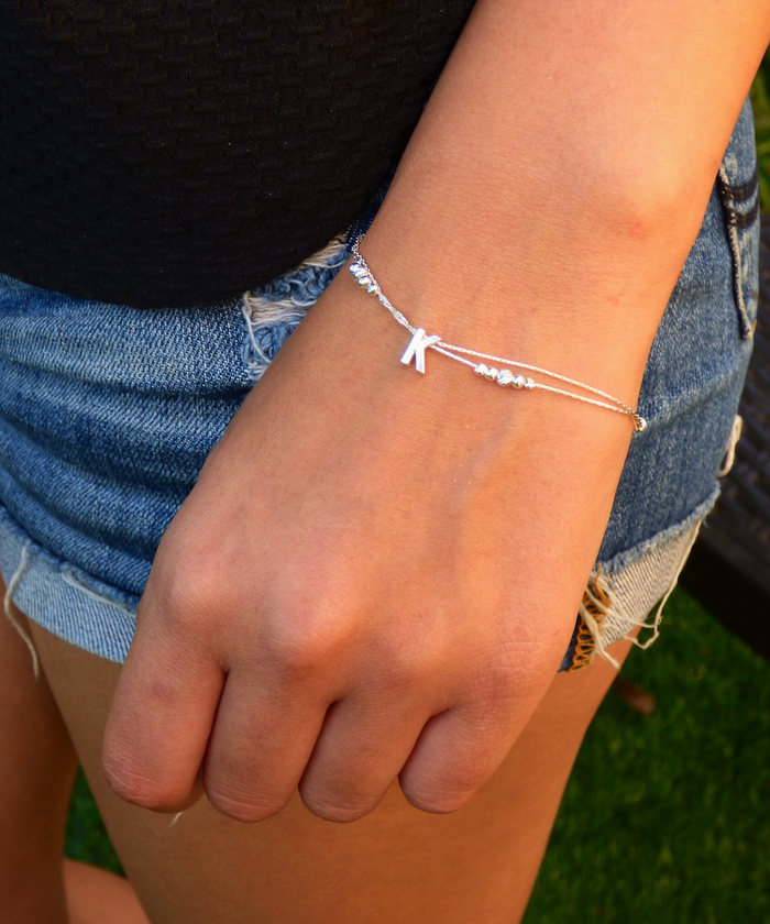 Chic model showcasing a personalized sterling silver initial bracelet with the letter 'K', adding a unique and stylish touch to any outfit.