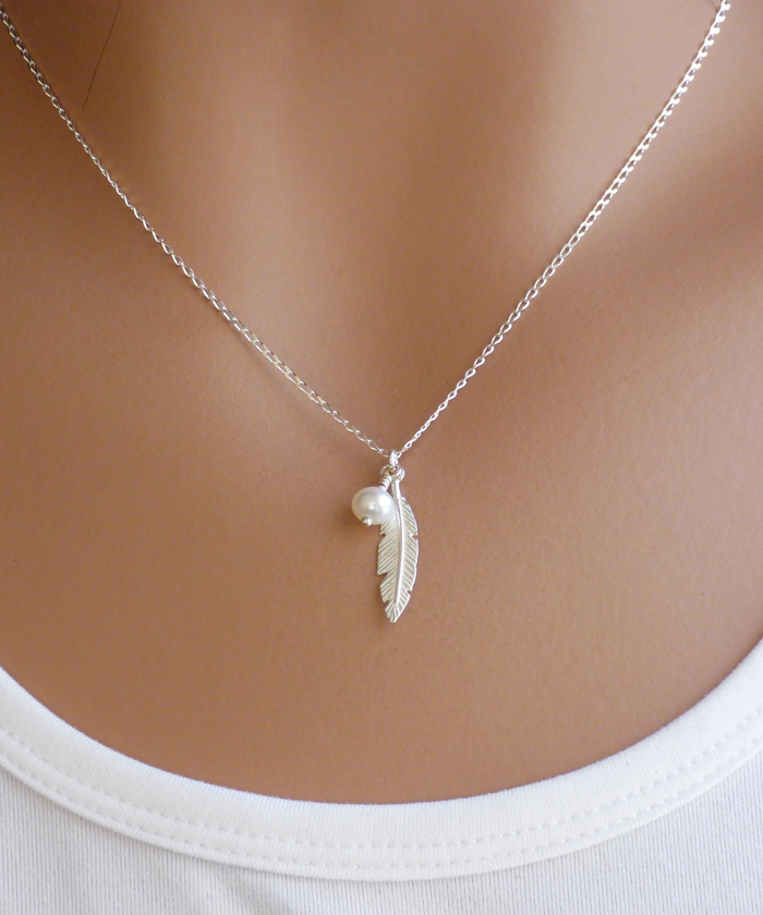 Model showcasing the elegance of our silver necklace with a delicate feather pendant and a tiny pearl