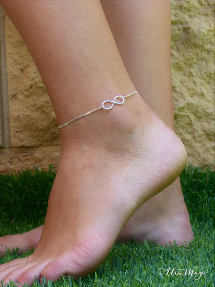 A woman is wearing an ankle bracelet with Infinity in silver -AlinMay