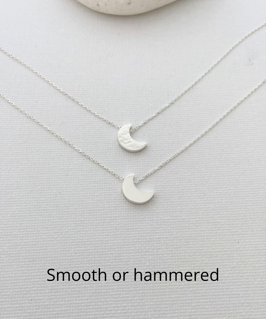 The picture shows two sterling silver moon necklaces in smooth finish and hammered finish on a white surface.