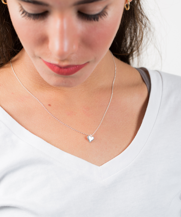 The model wears a dainty sterling silver necklace with a tiny heart pendant - AlinMay