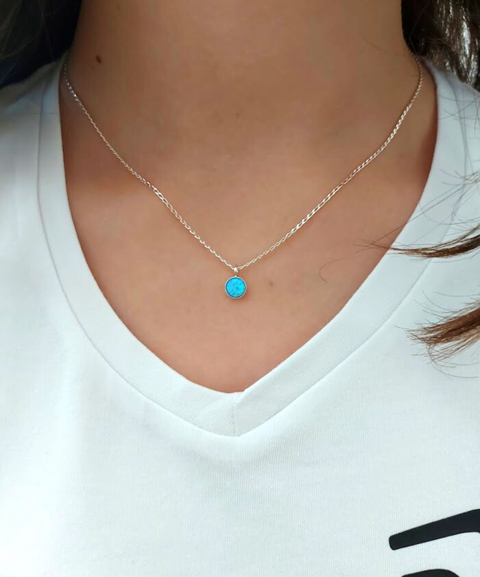 "Model showcasing the elegance of our silver necklace with a stunning blue opal pendant."