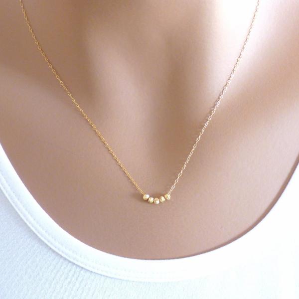 A woman is wearing tiny five beads necklace in Gold filled.