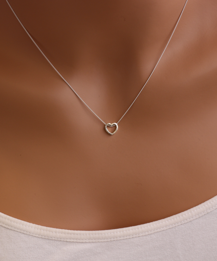 Model wearing a hammered heart necklace made of sterling silver. The necklace features a heart-shaped pendant that has been handcrafted with a unique design, giving it a minimalist yet trendy appearance-AlinMay
