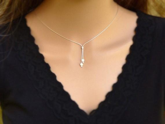 A woman is wearing a minimalist silver lariat necklace with two White beads-AlinMay