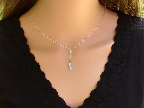 A woman is wearing a minimalist silver lariat necklace with a two Blue beads-AlinMay