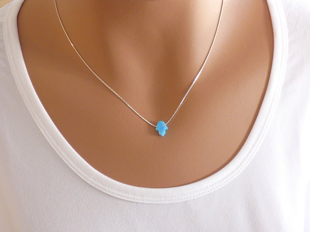 A woman is wearing a minimalist sterling Silver necklace with a Blue Hamsa hand-AlinMay
