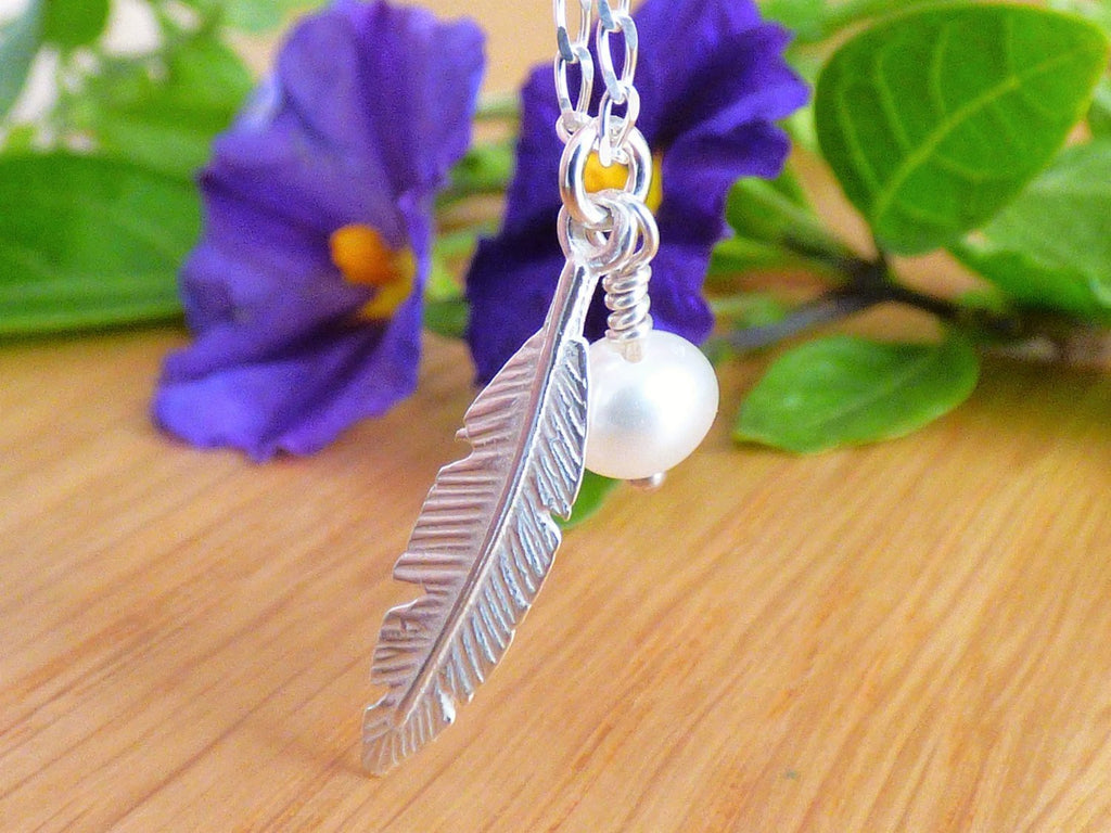 A delicate Silver 925 feather with a white tiny pearl on a delicate links chain.